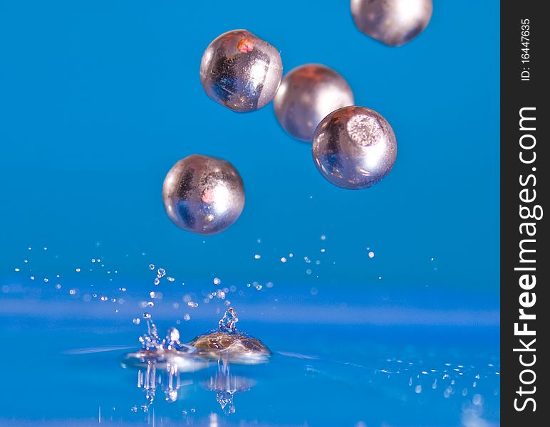 Marbles falling into blue water