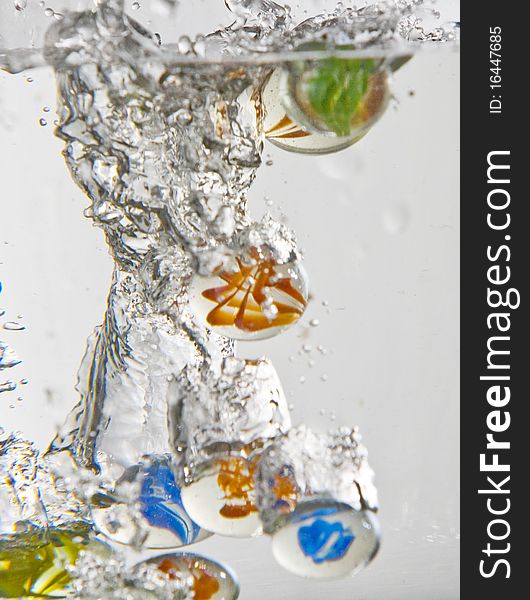 Marbles falling into water with white background. Marbles falling into water with white background