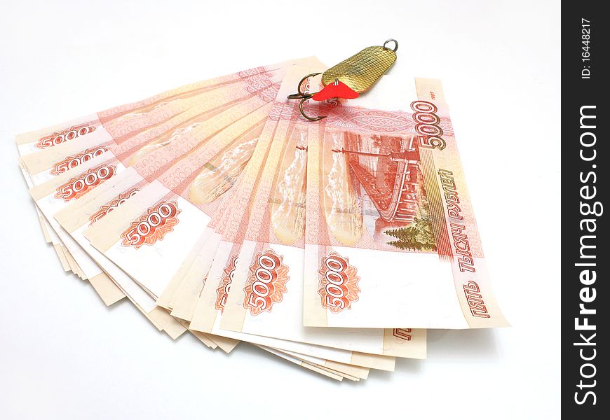 The Russian five-thousandth banknotes lie in bulk on a white background with a fishing spinner.