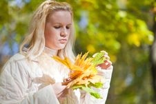 Girl Looks At A Bouquet Of Yellow Leaves Stock Image