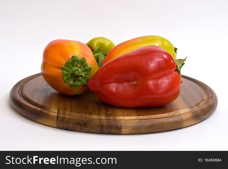 Colorful paprikas on wooden kitchen board isolated