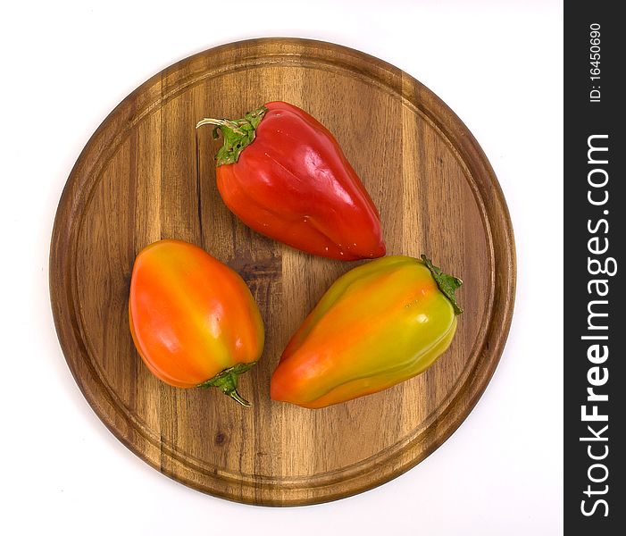 Colorful paprikas on wooden kitchen board isolated