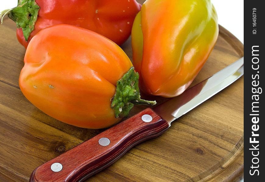 Colorful paprikas on wooden kitchen board isolated