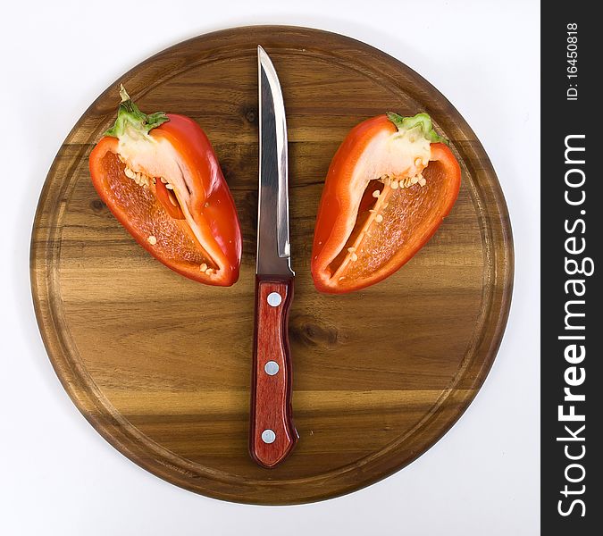 Red pepper on wooden kitchen board with knife