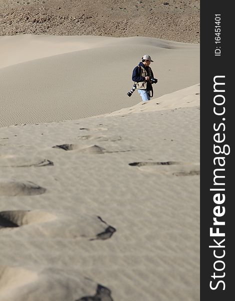 A photographer is walking in desert in Tibet, China. A photographer is walking in desert in Tibet, China