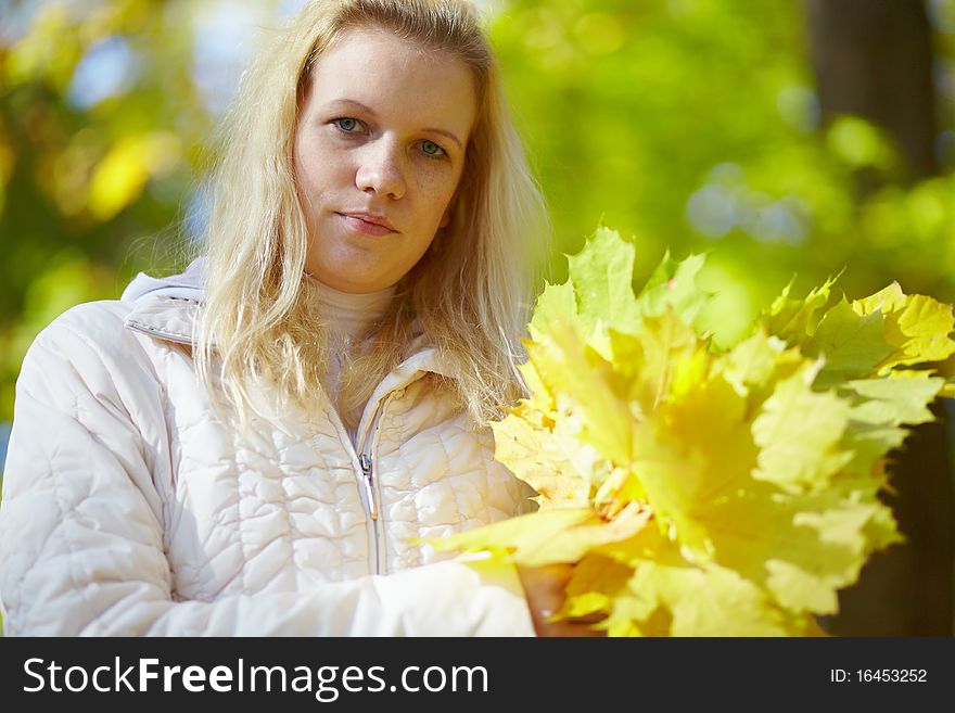 Beautiful blonde with a bouquet maple leaves