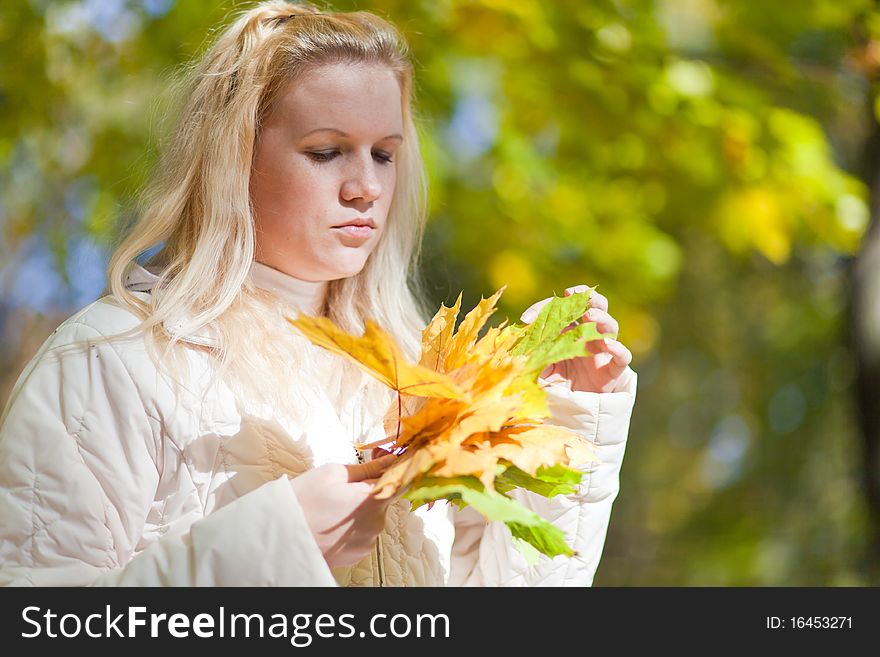 Girl looks at a bouquet of yellow leaves