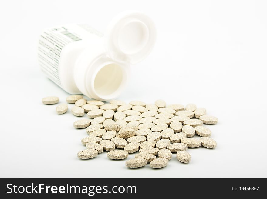 Heap of grassy tablets with a jar on a white background