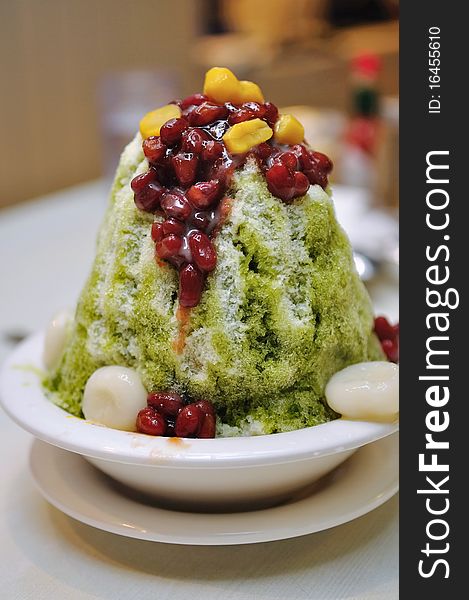 Bowl of Japanese green tea ice dessert topped with red beans