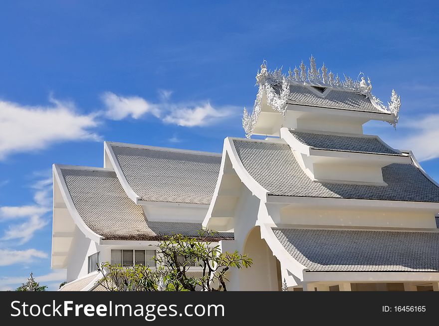 Roofs of Wat Rong Khun temple against blue sky