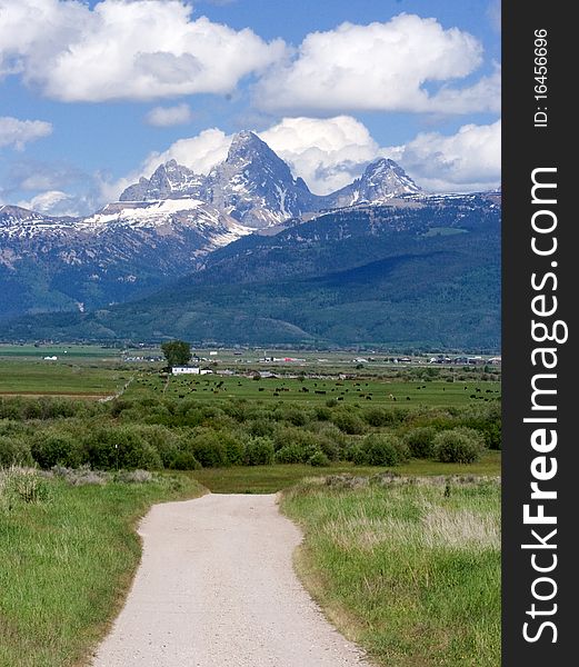 Dirt road leading to farmland at the base of the Teton mountains. Dirt road leading to farmland at the base of the Teton mountains