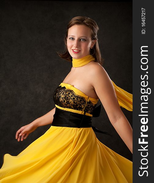 Portrait of young woman young woman in a yellow dress on dark background
