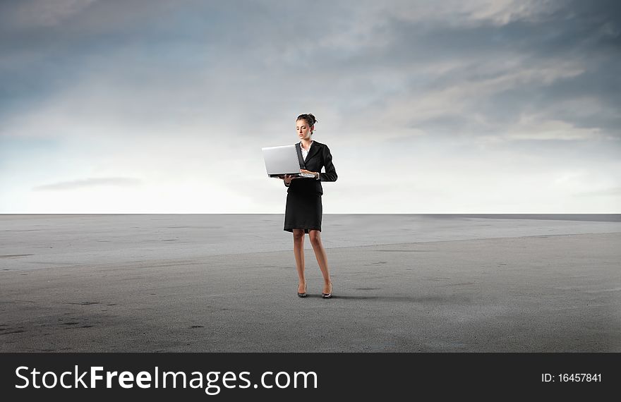 Businesswoman using a laptop in a desert. Businesswoman using a laptop in a desert