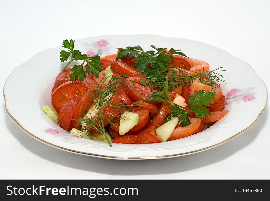 Salad with fresh ripe tomatoes and cucumbers on a plate on a white background. Salad with fresh ripe tomatoes and cucumbers on a plate on a white background