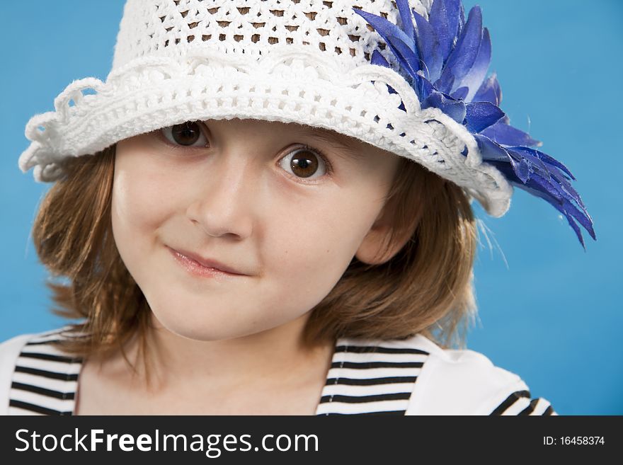 Portrait of the lovely girl in a white knitted cap. Blue background. Portrait of the lovely girl in a white knitted cap. Blue background.