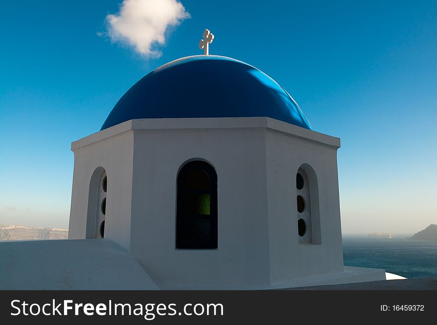 View on the sea and a typical greek church in the steep coast on top of the caldera in Santorini, Greece, all in the greek national colors white and blue. View on the sea and a typical greek church in the steep coast on top of the caldera in Santorini, Greece, all in the greek national colors white and blue.