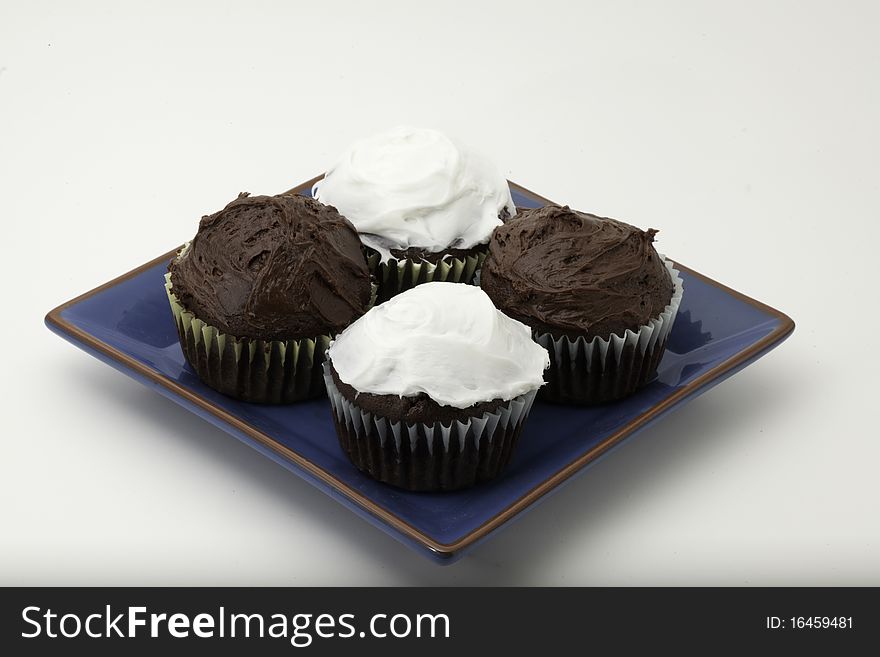 Chocolate cupcakes with chunks of chocolate on a plate with icing. Chocolate cupcakes with chunks of chocolate on a plate with icing.