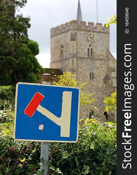 A signpost denoting a dead end on the side of a country lane with a church in the background. A signpost denoting a dead end on the side of a country lane with a church in the background