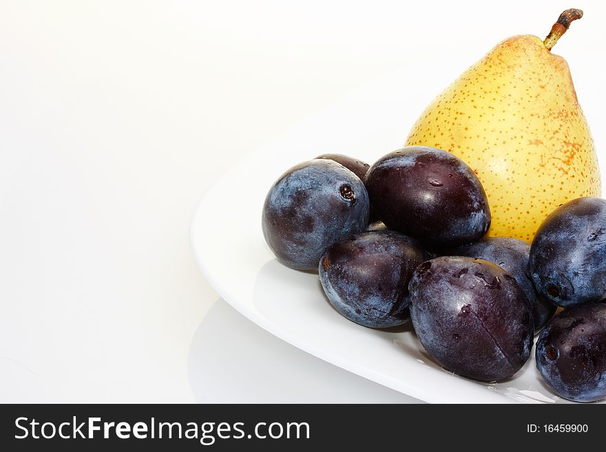 Yellow Pear On A White Plate With Plums