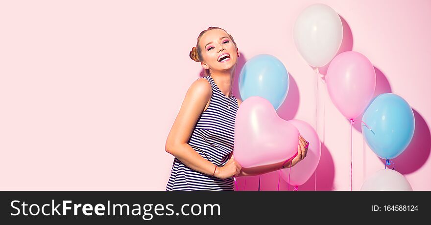 Beauty girl with colorful air balloons laughing over pink background. Beautiful Happy Young woman on birthday holiday party