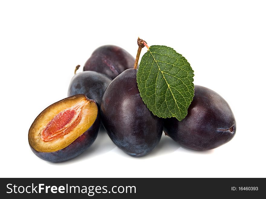 Ripe, juicy plums with a green leaf on white background. Ripe, juicy plums with a green leaf on white background