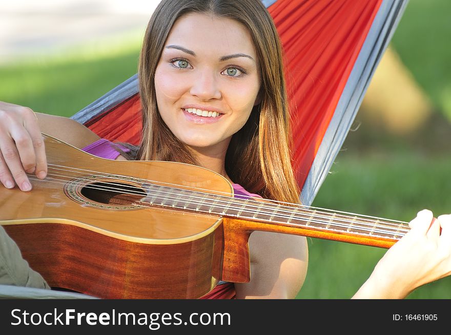 Pretty girl laying in a hammock and playing guitar. Pretty girl laying in a hammock and playing guitar