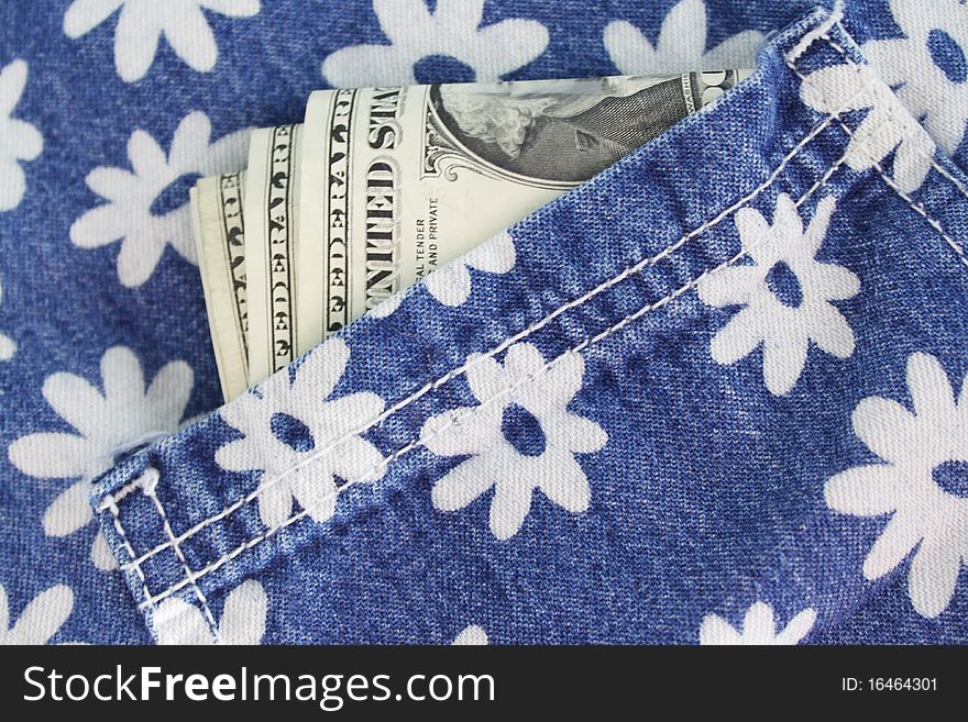 Some bills sticking out of the pocket of jeans with a flower pattern. Some bills sticking out of the pocket of jeans with a flower pattern.