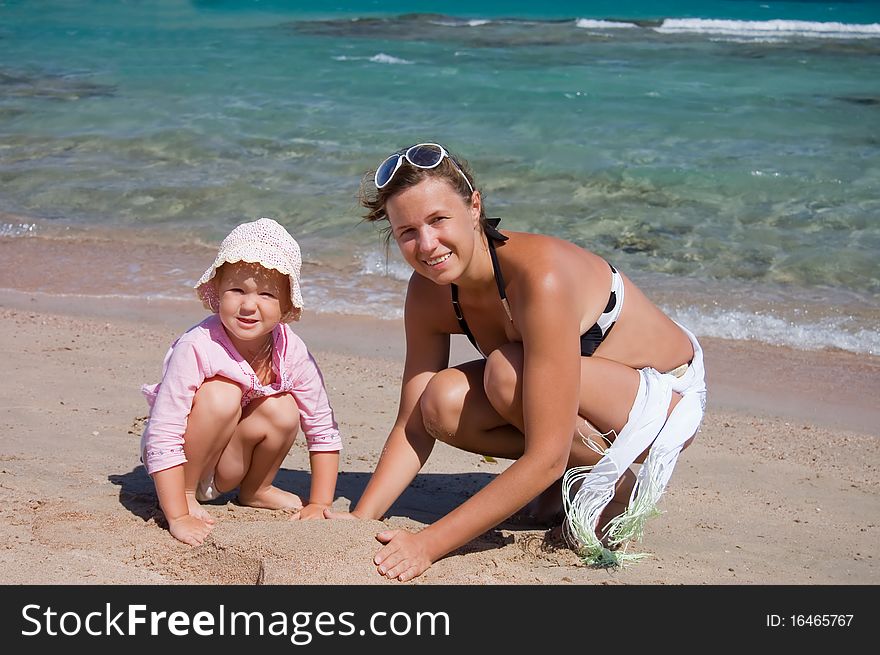 Mother With The Child Playing With Sand On Beach