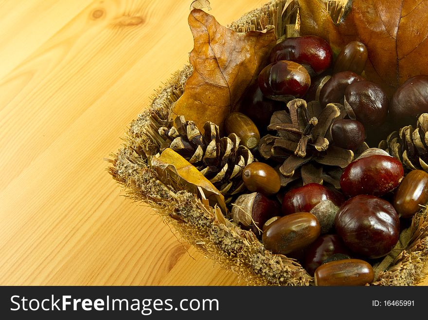 Chestnuts, acorns and leaves in a basket. Chestnuts, acorns and leaves in a basket