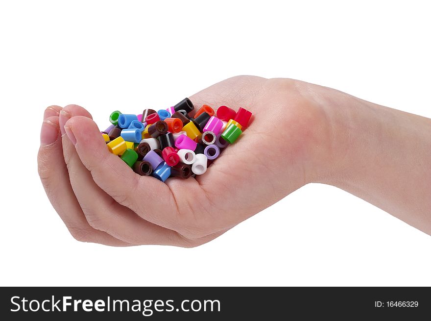 Plastic colorful mosaic particles in the child hand isolated over white background. Plastic colorful mosaic particles in the child hand isolated over white background