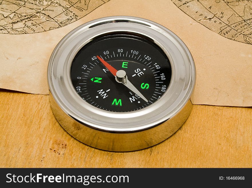 Compass with an old paper on a wooden background