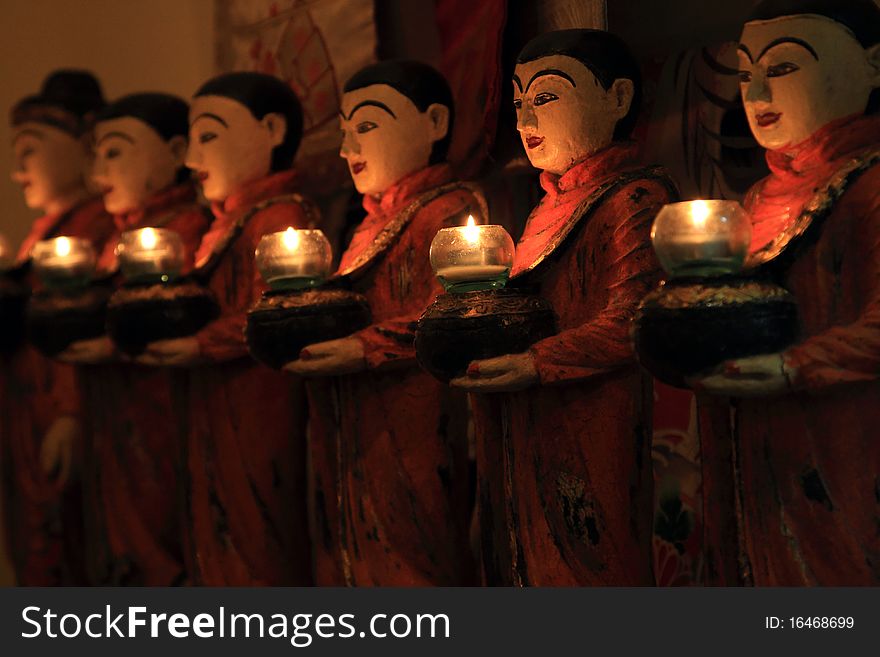 Row of Buddhist monk statues holding candlestick ,displayed in the night market,Bangkok,Thailand