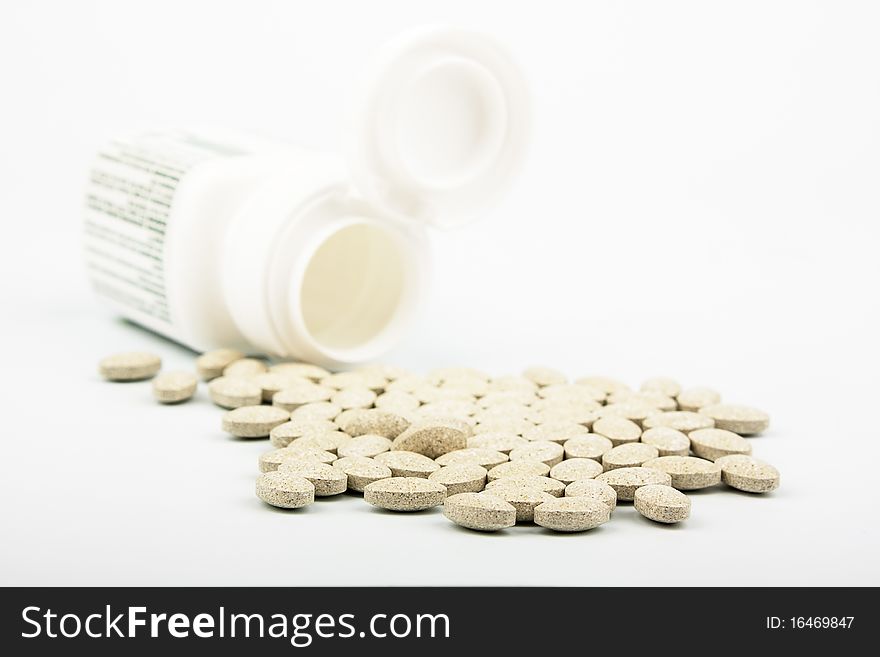 Heap of grassy tablets with a jar on a white background