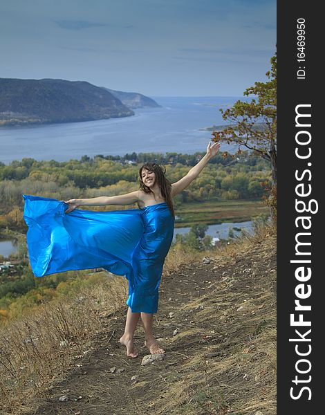 A young girl in a blue dress dancing on a mountain