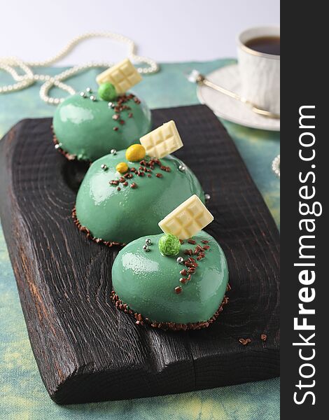 Homemade bright mousse cakes Hearts with green mirror icing, Closeup, vertical orientation