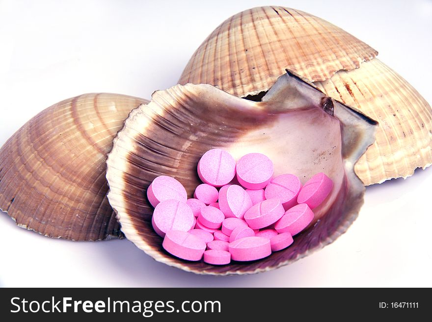 Pink pills spread in a sea shell