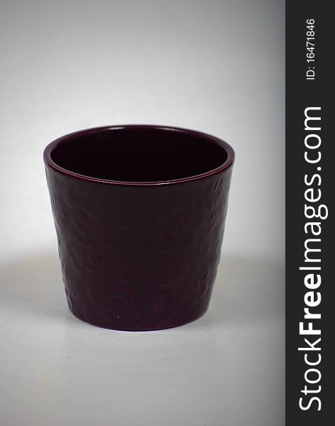 Purple ceramic vase for flowers and dirt.