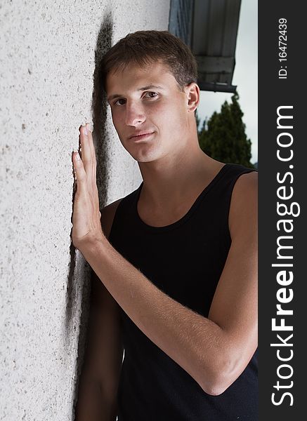 Young teenage boy leaning against a wall in anurban setting. Young teenage boy leaning against a wall in anurban setting.