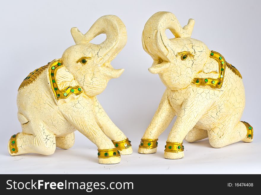 White elephants engraving from wood with gold dressed kneeing on the floor and raise his nose on the top.