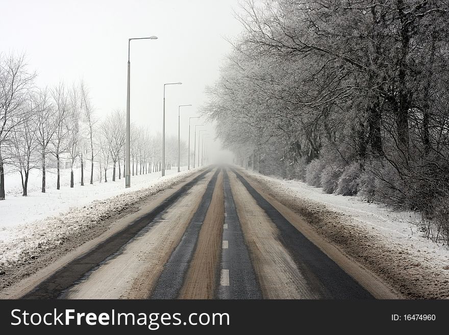 Long, snowy road on a foggy winter day apart from the city. Long, snowy road on a foggy winter day apart from the city.