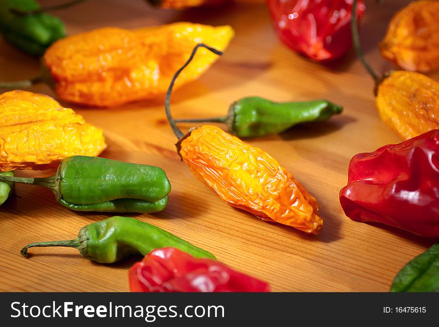 Collection of multicolored hot chili peppers on a wooden table. Selective focus. Shallow depth of field. Collection of multicolored hot chili peppers on a wooden table. Selective focus. Shallow depth of field.