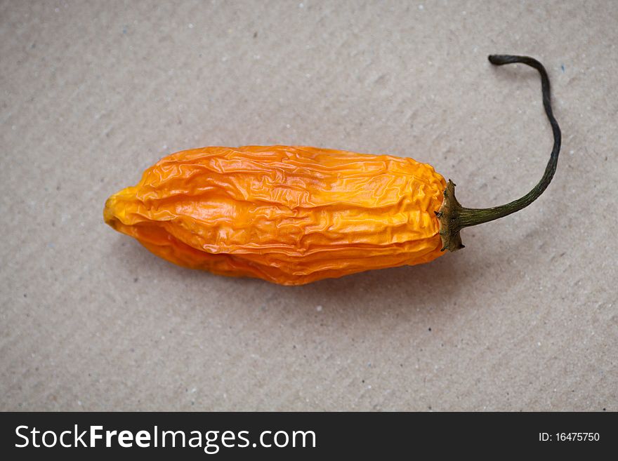 Hot orange chili peppers on a cardboard background. Hot orange chili peppers on a cardboard background