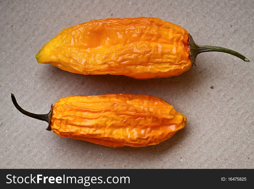 Two hot chili peppers on a cardboard background. Two hot chili peppers on a cardboard background