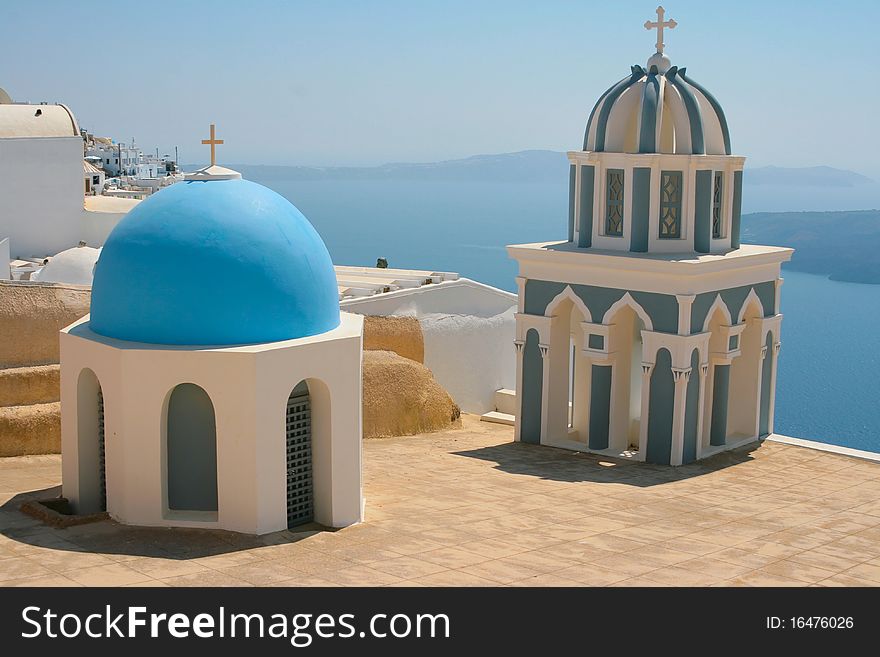 Two classic small beautiful churches in Fira on island of Santorini, Greece. Caldera view on a background. Two classic small beautiful churches in Fira on island of Santorini, Greece. Caldera view on a background.