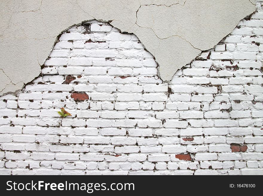 Red brick shows through a cracked stucco exterior. Red brick shows through a cracked stucco exterior.