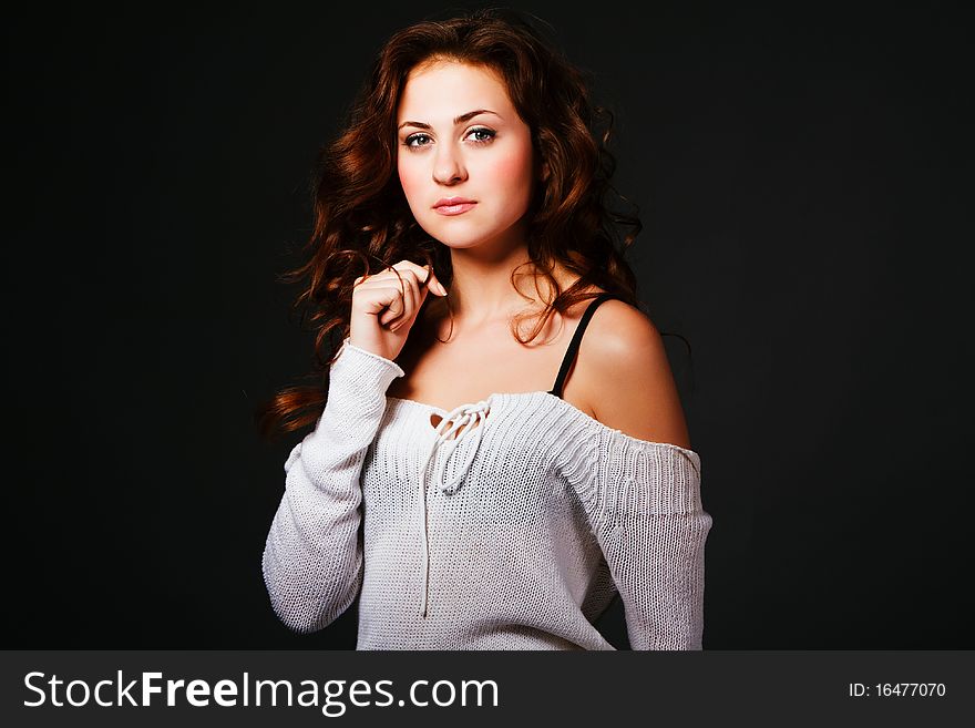 Portrait of a attractive young brunette in sweater on gray background