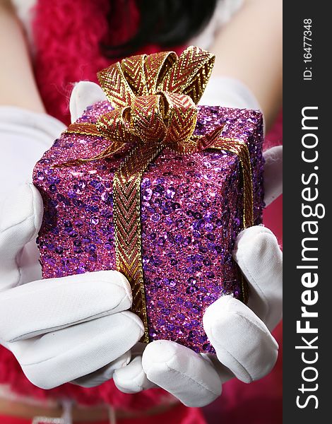 Sequence decorated christmas gift held by white gloves with holiday woman in background. Sequence decorated christmas gift held by white gloves with holiday woman in background.