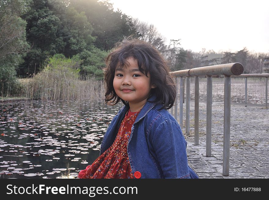 The portrait of a Malay girl that Smiles while sitting by a lake in Spring Season. The portrait of a Malay girl that Smiles while sitting by a lake in Spring Season