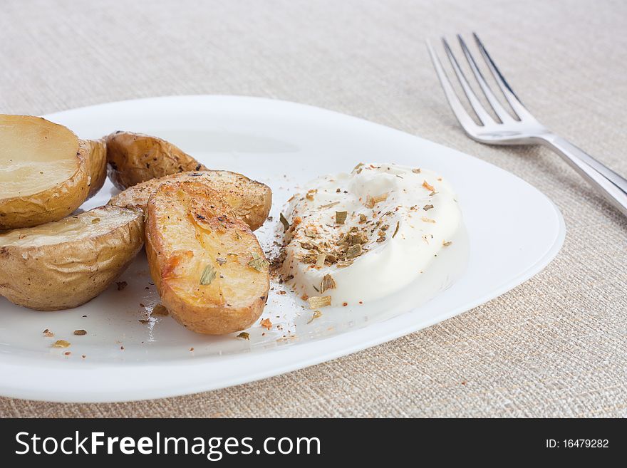 Baked potato on white plate with sour cream