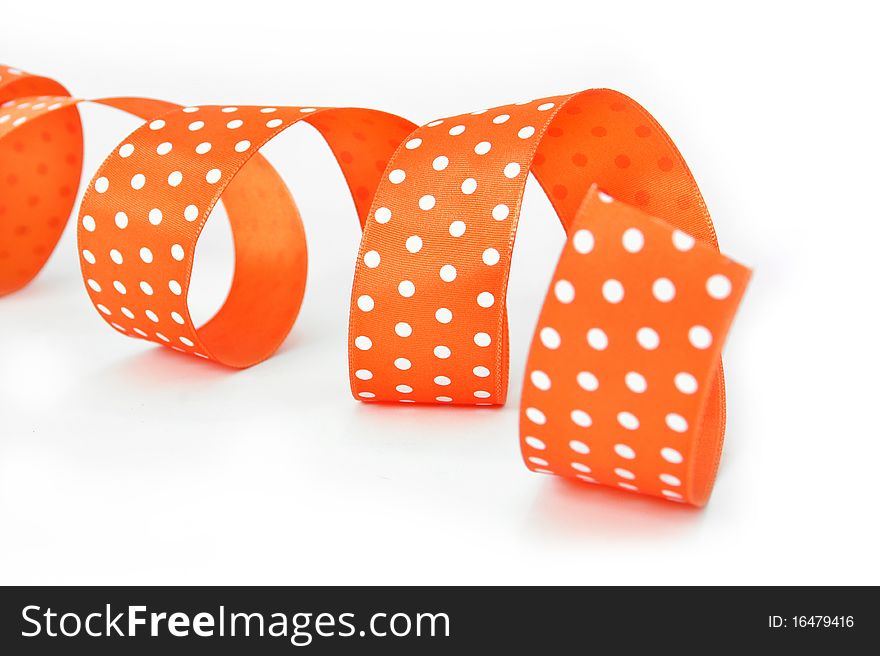 An orange fabric ribbon with white polkadots, curled and with a shallow DOF. An orange fabric ribbon with white polkadots, curled and with a shallow DOF